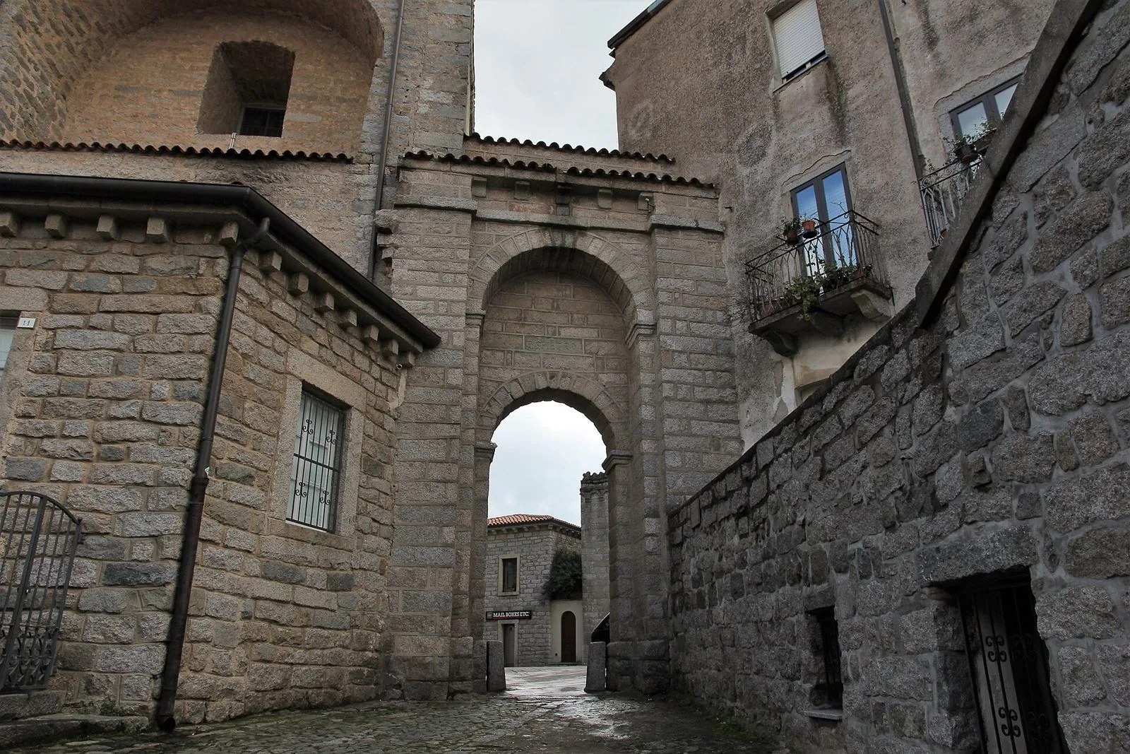 Un vicolo del centro storico di Tempio Pausania con edifici e un arco in blocchi di granito
