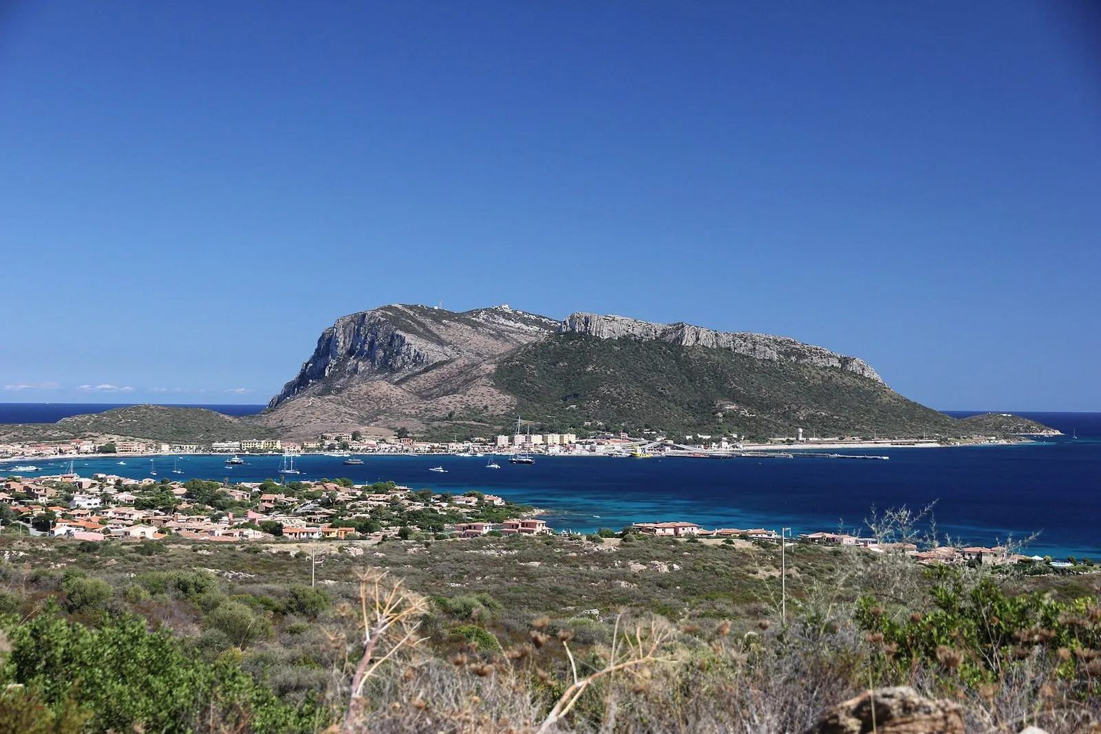Il promontorio di Capo Figari che domina il paese e il porto di Golfo Aranci, con il mare blu in primo piano